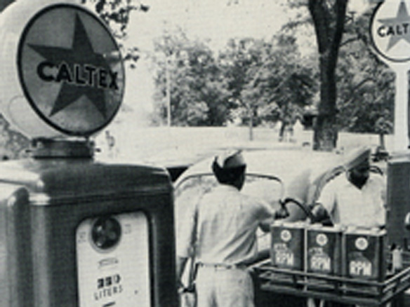 Black and white photo of two Caltex attendants fuelling up a car