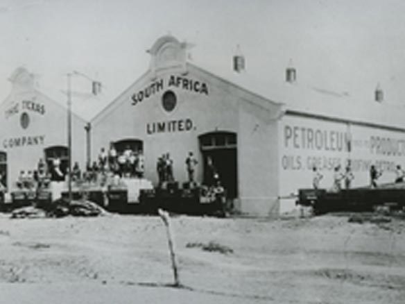 Black and white photo of people gathering outside two South Africa Limited buildings