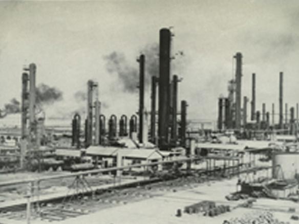 Black and white photo of smoking fuel factory stacks