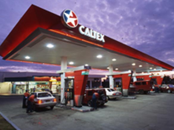 A brightly lit Caltex station with cars fuelling up