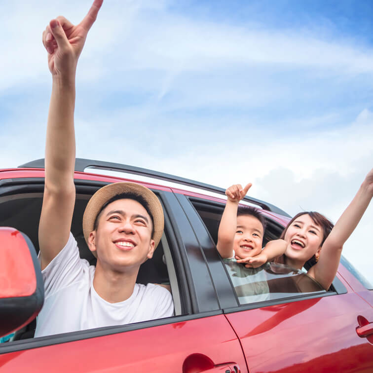 Happy family leaning out of their car windows and pointing towards the sky
