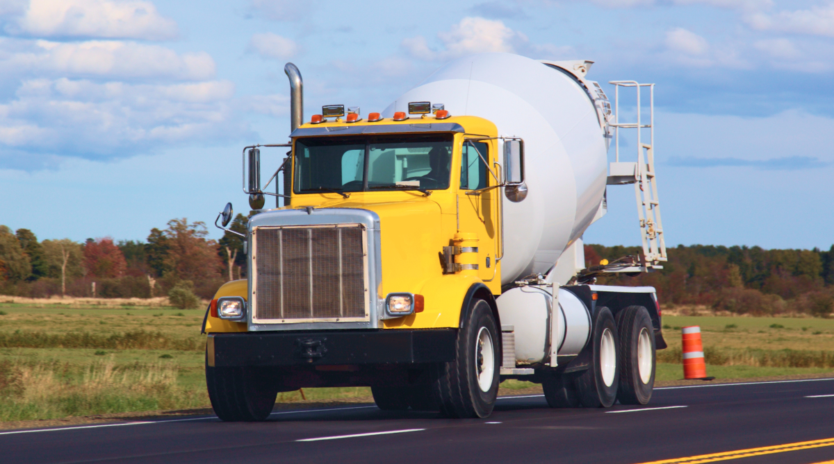 Yellow cement truck driving down road