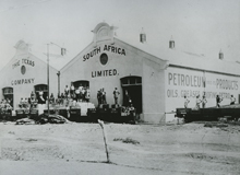 Black and white photo of people gathering outside two South Africa Limited buildings