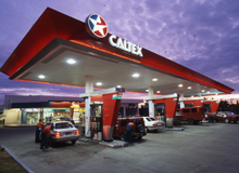A brightly lit Caltex station with cars fuelling up