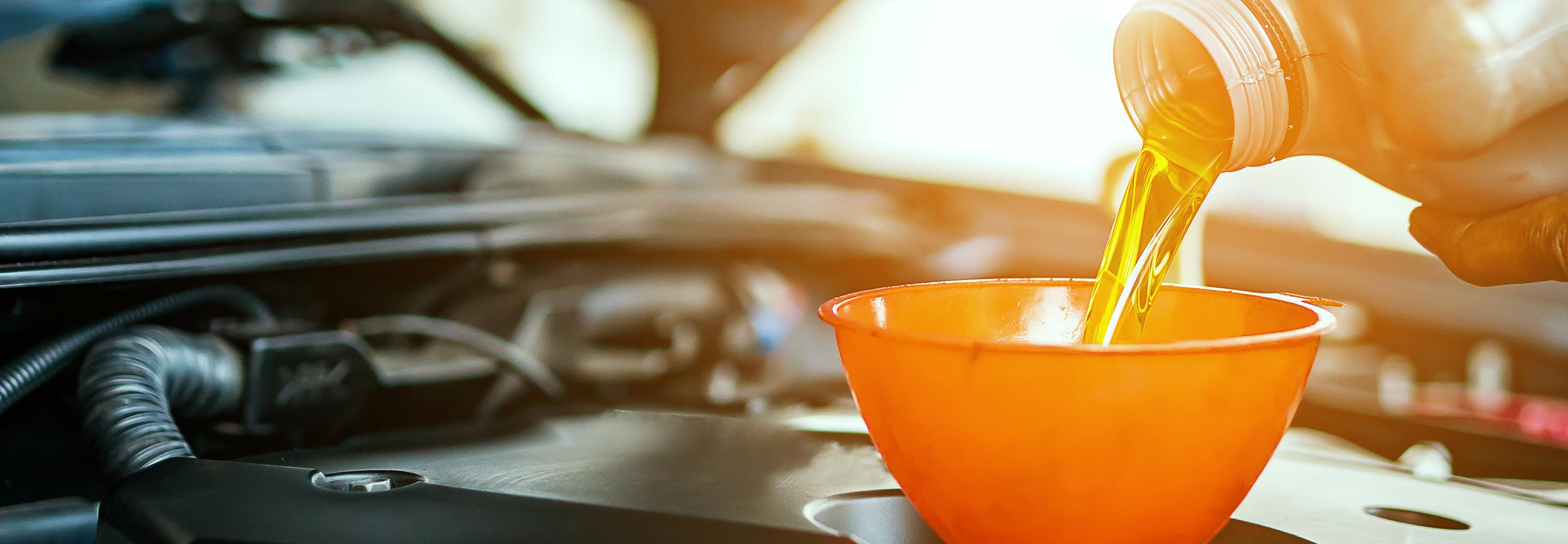 Pouring engine oil with a funnel into a car