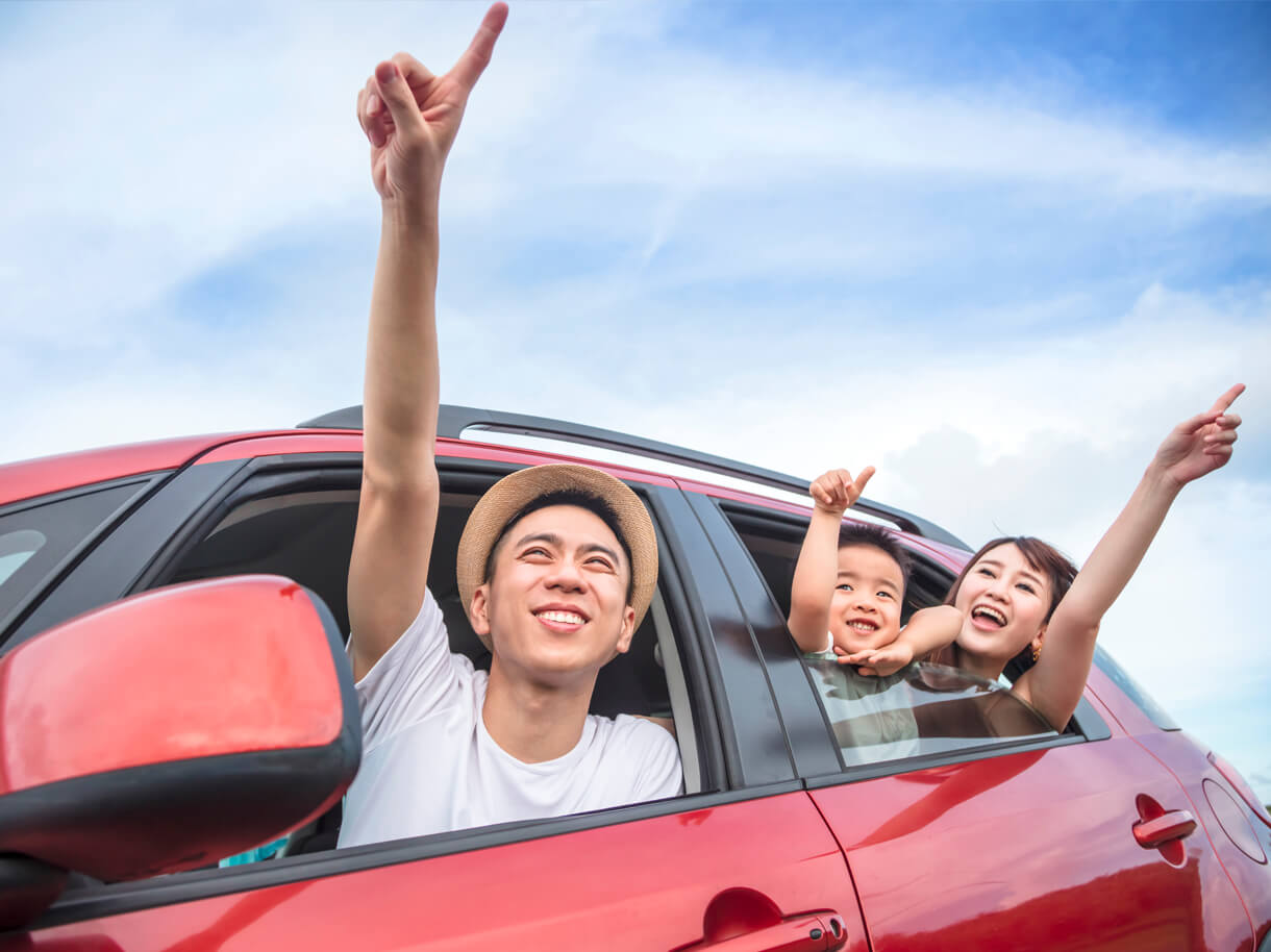 Happy family leaning out of their car windows and pointing towards the sky